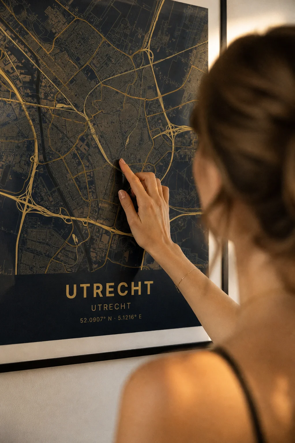 Hand die een ingelijste kaartposter van Utrecht aanraakt